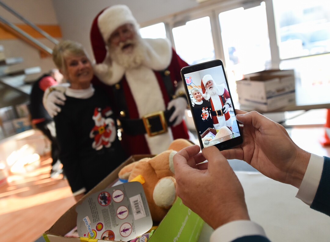 (Francisco Kjolseth  |  The Salt Lake Tribune)  Candy Michaels poses for a photograph with Santa played by Merlin Taylor as a team of volunteers assembles holiday packages for low income families on Tuesday, Dec. 3, 2019. The Granite Education Foundation's Santa Sacks program, started in 2009, is expected to help over 3000 students across 60 schools in the district.