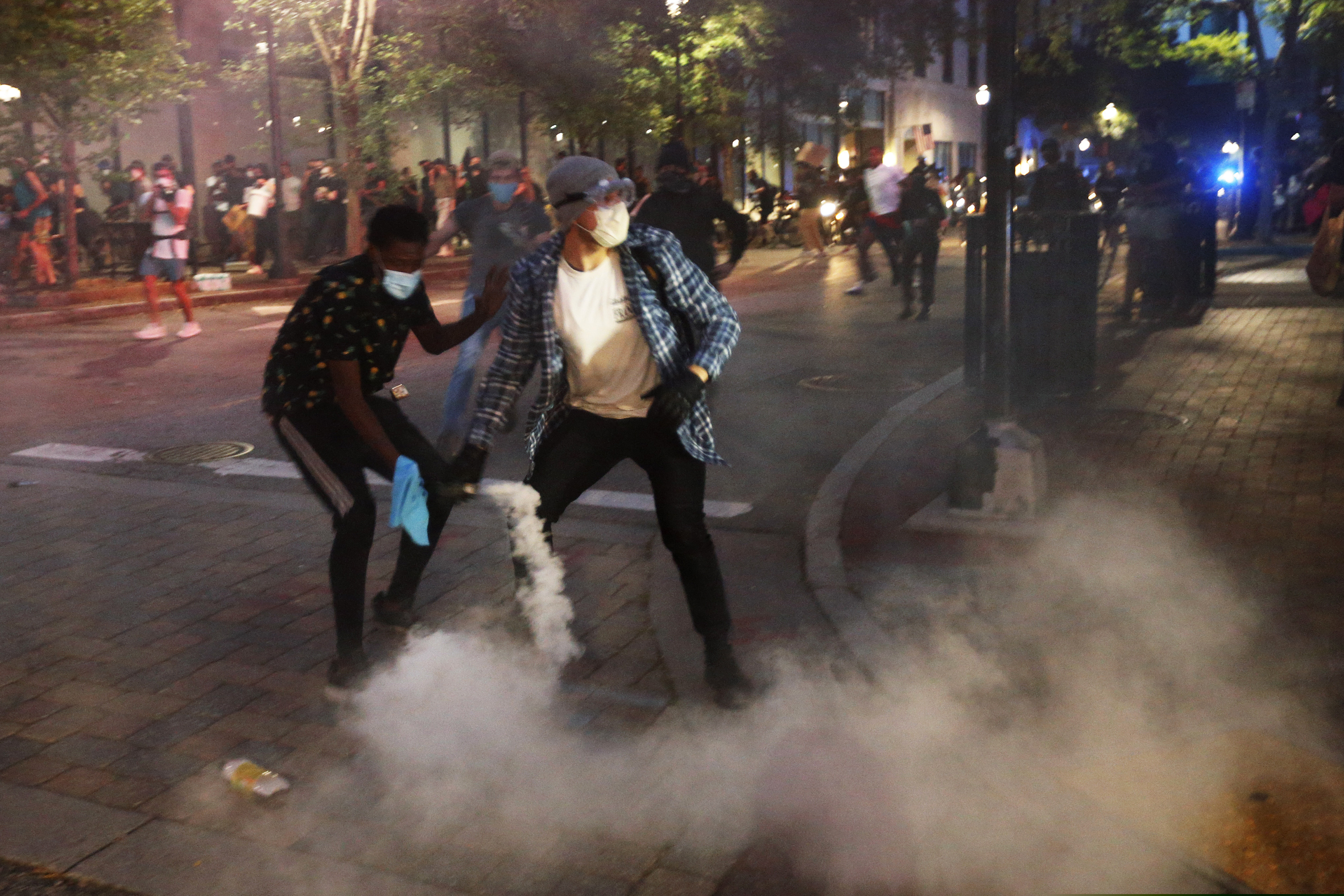 (Steve Helber | AP)  A protester tosses a smoke bomb towards police during a third night of unrest Sunday, May 31, 2020, in Richmond, Va. Gov. Ralph Northam issued a curfew for this evening. The smoke bomb was ignited by a protester.