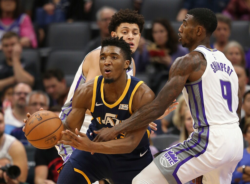 Utah Jazz guard Donovan Mitchell, center, passes out of a double-team by Sacramento Kings' Justin Jackson, left and Iman Shumpert during the first quarter of an NBA preseason basketball game Thursday, Oct. 11, 2018, in Sacramento, Calif. (AP Photo/Rich Pedroncelli)