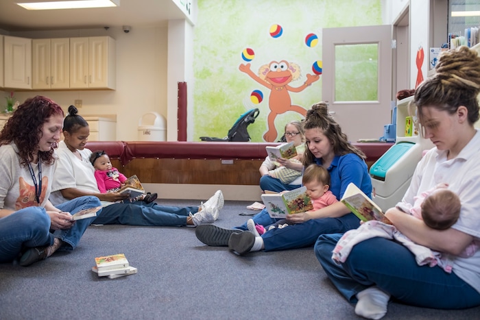 From left: case worker Sue Urish and inmates LaTonya Jackson, with her 5-month-old daughter, Olivia Walton; Michelle Neaveill, with her 3-month-old son, Dalton Neaveill; Destiny Doud, with her 10-month-old daughter, Jaelynn Purcell; and Christine Duckwitz, with her 2-month-old daughter, Isabelle Mansker, read together at the Decatur Correctional Center in Decatur, Ill., on April 9, 2018. (Whitney Curtis |The Washington Post)