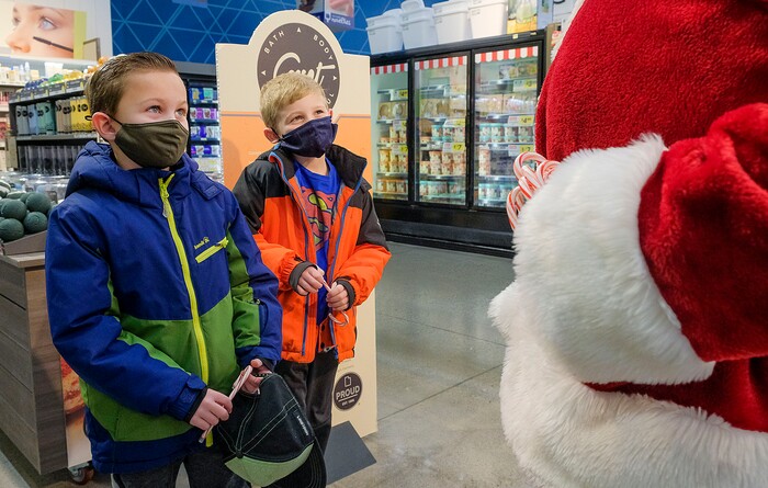 (Leah Hogsten  |  The Salt Lake Tribune)  Brothers Hudson Bench, 9, and Jameson Bench, 7, tell Santa what they would like for Christmas and promise to leave cookies for him at Macey's grocery store on Thursday. The jolly fat man also greeted Macey's guests who scheduled a grocery pickup time, Dec. 24, 2020.