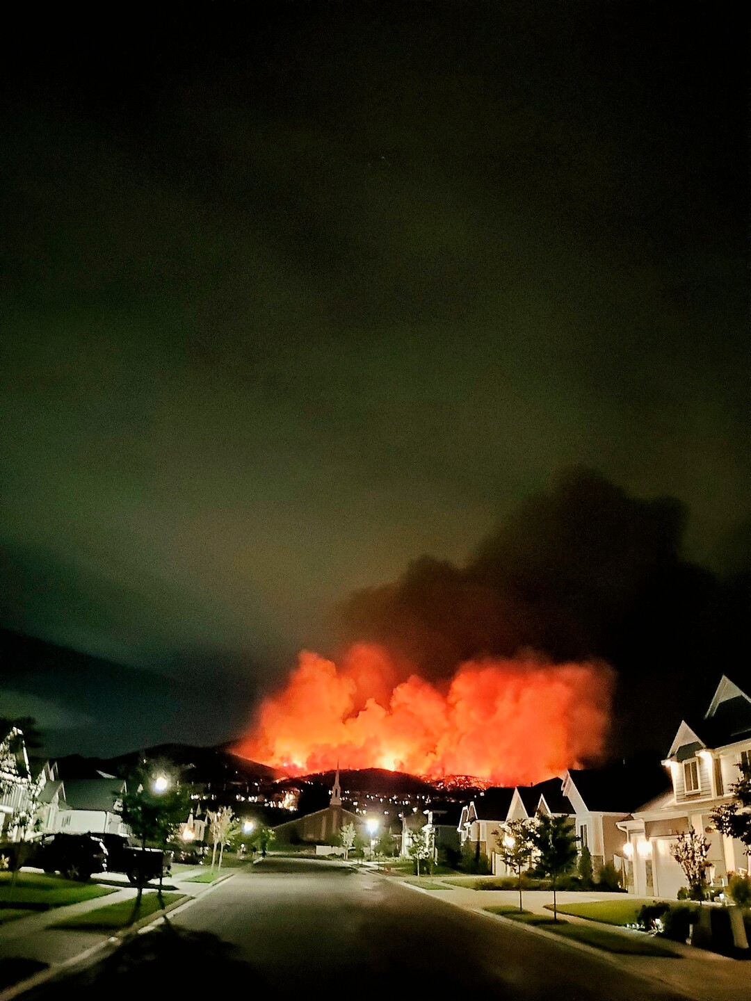 The Traverse Fire burns behind homes in Lehi, Utah, Sunday, June 28, 2020. Officials say fireworks caused the wildfire and forced evacuations early Sunday morning. (Justin Reeves via AP)