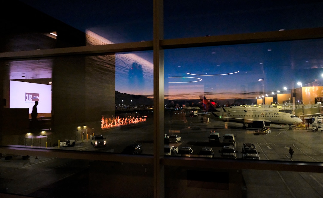 (Leah Hogsten  |  The Salt Lake Tribune) The Salt Lake City International Airport commemorated its 100-year anniversary, Dec. 21, 2020. Reflections of party attendees are reflected in the glass within the Greeting Room as a Delta Jet prepares to leave the hub.