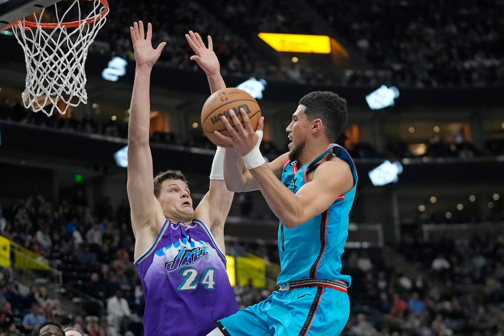 Phoenix Suns guard Devin Booker, right, goes to the basket as Utah Jazz center Walker Kessler (24) defends during the second half of an NBA basketball game Monday, March 27, 2023, in Salt Lake City. (AP Photo/Rick Bowmer)