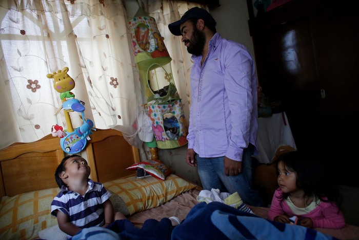In this Aug. 23, 2017 photo, 1-year-old Jose Leonardo, known as Leon, looks up at his father Alejandro Garcia as his dad tries to get him dressed for the day in the room Leo shared with his mother Jessica Sevilla, in her family's home in Villa Cuauhtemoc, Mexico state. After Jessica's murder, her ex, Alejandro, is staying in the room together with their son. (AP Photo/Rebecca Blackwell)