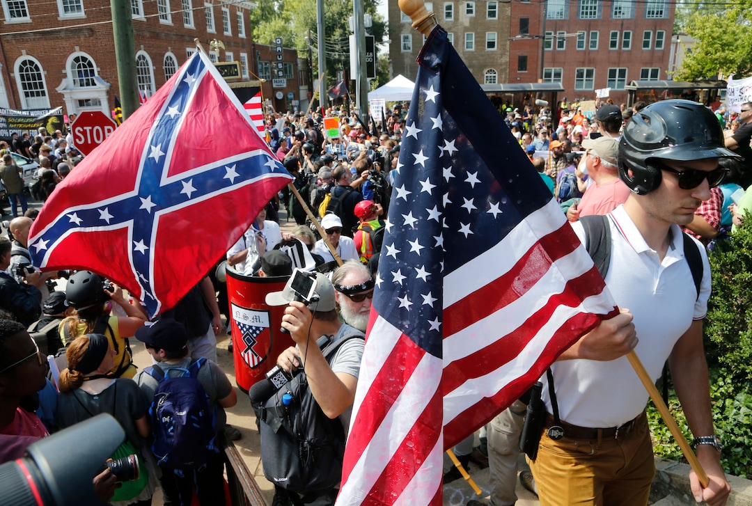 White nationalist demonstrators walk into Lee park surrounded by counter demonstrators in Charlottesville, Va., Saturday, Aug. 12, 2017. Gov. Terry McAuliffe declared a state of emergency and police dressed in riot gear ordered people to disperse after chaotic violent clashes between white nationalists and counter protestors. (AP Photo/Steve Helber)
