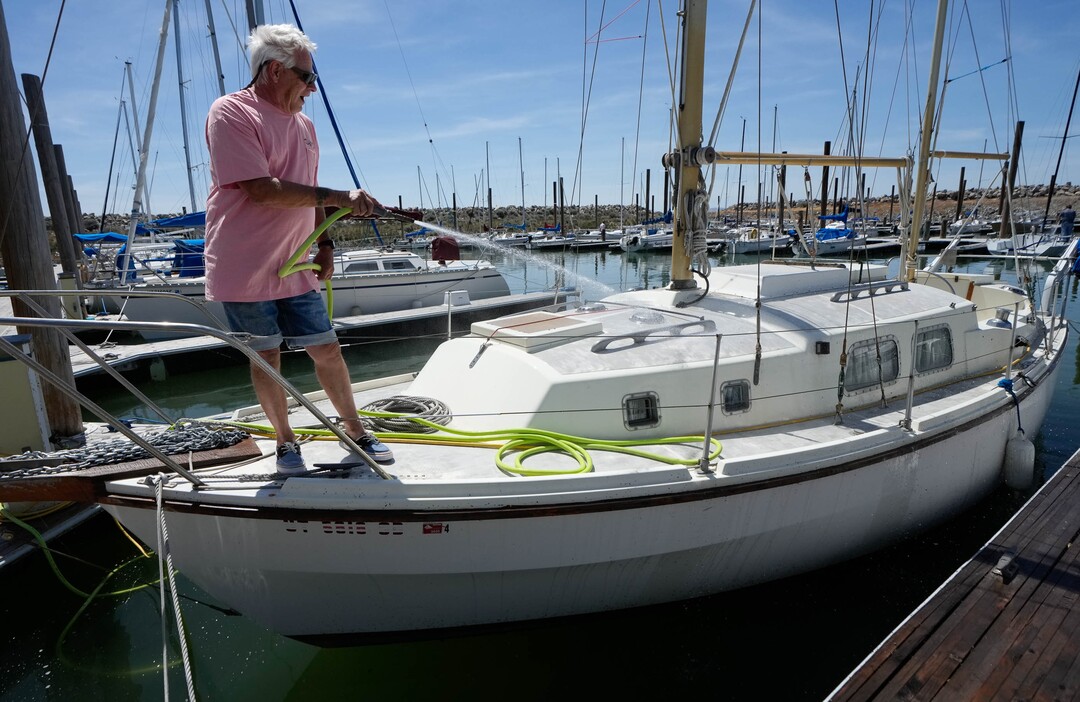 (Francisco Kjolseth  |  The Salt Lake Tribune) Going by the name “old captain Blinkey,” bugs and salt are sprayed off before heading out for a sail on the Great Salt Lake during Sailfest on Saturday, June 15, 2024.