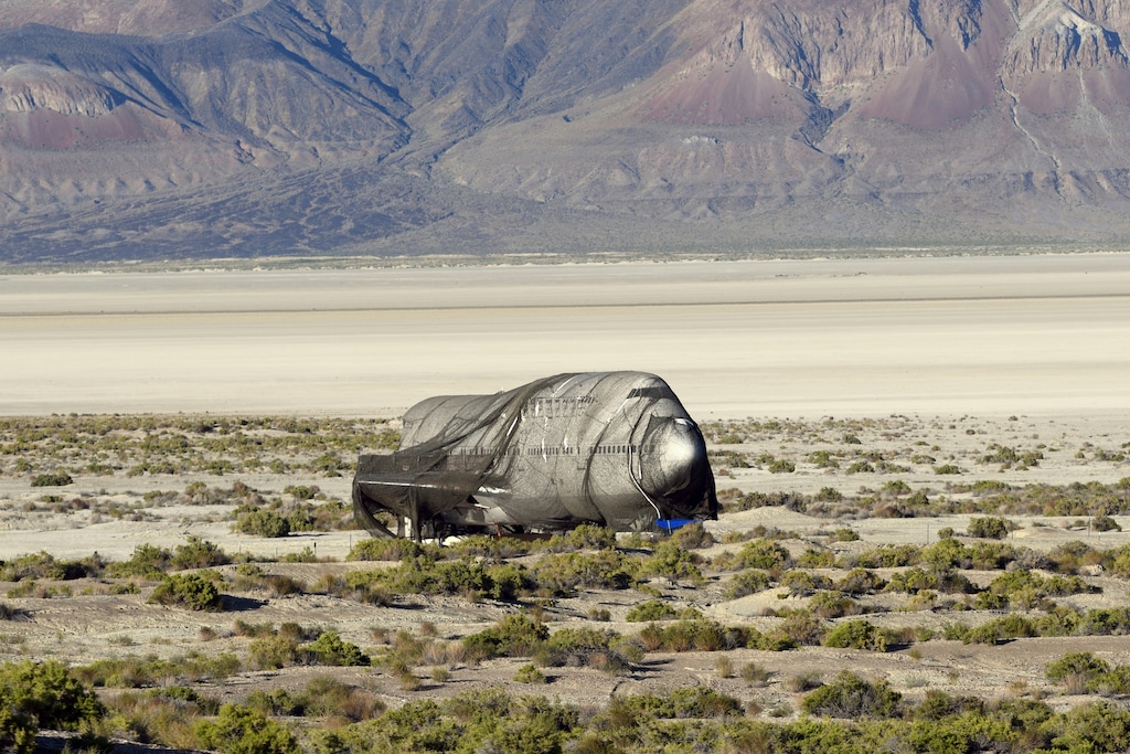 In this July 22, 2019 photo, a 747 fuselage that has been converted into a nightclub sits on private property under netting on the edge of the Black Rock Desert playa about 100 miles north of Reno, before it was moved last weekend into place as an art installation at the Burning Man festival. The jumbo jet sparked controversy last year when it got stuck in the desert for nearly a month. But it's builder secured a permit for this year's event after agreeing to post a performance bond with the U.S. Bureau of Land Management. (Sam Gross/The Reno Gazette-Journal via AP)