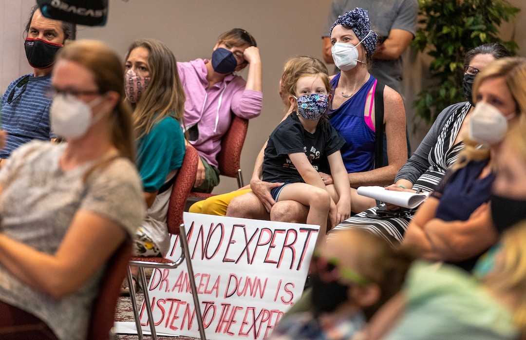 (Leah Hogsten | The Salt Lake Tribune) Celka van Dijk and her children Malin, 8, and Wilder, 5, on her lap attended Monday's press conference with a sign that read, "I'm no expert. Dr. Angela Dunn is. Listen to the expert." A group of Utah parents is suing the state for its ban on school districts enacting their own mask mandates  which they say leaves their kids unnecessarily unprotected and at-risk from COVID-19 in the classroom, Aug. 23, 2021.