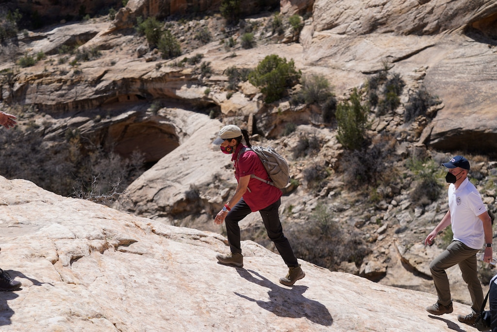 (Rick Bowmer | AP, pool) U.S. Interior Secretary Deb Haaland tours near ancient dwellings along the Butler Wash Trail with Utah Gov. Spencer Cox, right, and other officials during a visit to Bears Ears National Monument Thursday, April 8, 2021, near Blanding.