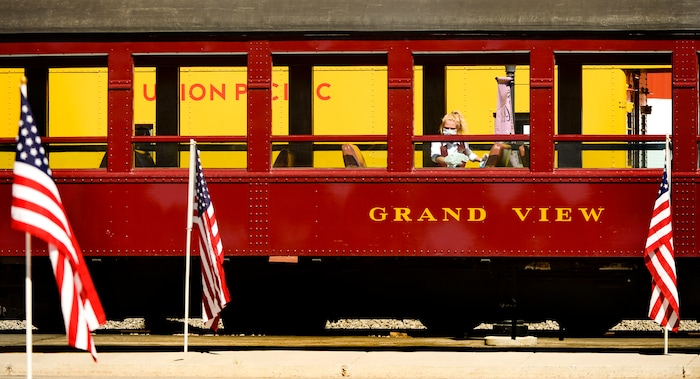(Leah Hogsten  |  The Salt Lake Tribune) A woman wipes down a passenger train car at the historic Heber Valley Railroad as American flags honor in part of the Heber City 2020 Memorial Day Drive By Tribute to remember and honor all of our military, past and present, men and women who serve or have served in our Armed Forces, May 25, 2020.