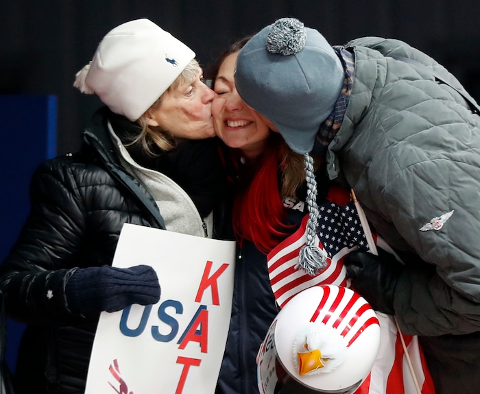 Katie Uhlaender of United States, center, is hugged and kissed by Jean Schaefer, left, and Dr. Brian Boxer Wachler in the finish area after the final run of the women's skeleton competition at the 2018 Winter Olympics in Pyeongchang, South Korea, Saturday, Feb. 17, 2018. Schaefer is the mother of deceased American bobsledder Steve Holcomb and Wachler is a Holcomb family friend and doctor. They came to support Uhlaender, who was friends with Holcomb. (AP Photo/Andy Wong)