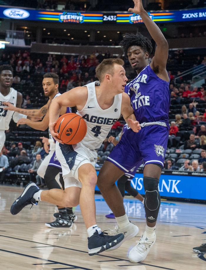 (Rick Egan  |  The Salt Lake Tribune)      Utah State Aggies guard Crew Ainge (4) takes the ball down the middle, as Weber State Wildcats guard Israel Barnes (12) defends, in basketball acton in the Beehive Classic, between against the Utah State Aggies and Weber State Wildcats, a the Vivint Smart Home Arena, Saturday December 8, 2018.

 