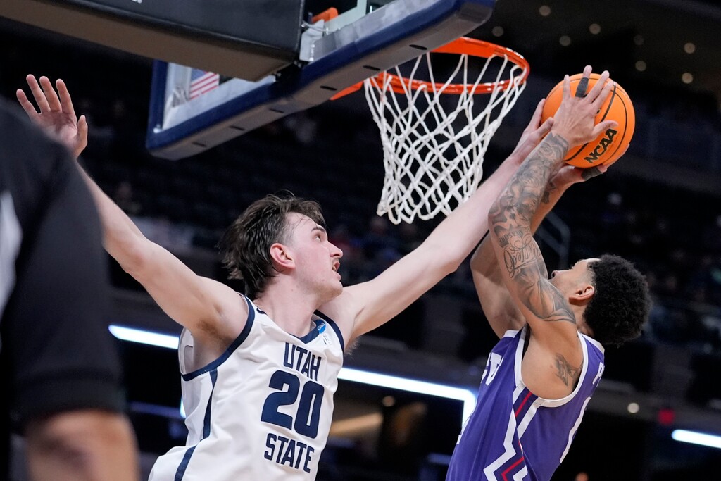 Utah State center Isaac Johnson (20) blocks a shot by TCU guard Micah Peavy in the second half of a first-round college basketball game in the NCAA Tournament, Friday, March 22, 2024, in Indianapolis. (AP Photo/Michael Conroy)