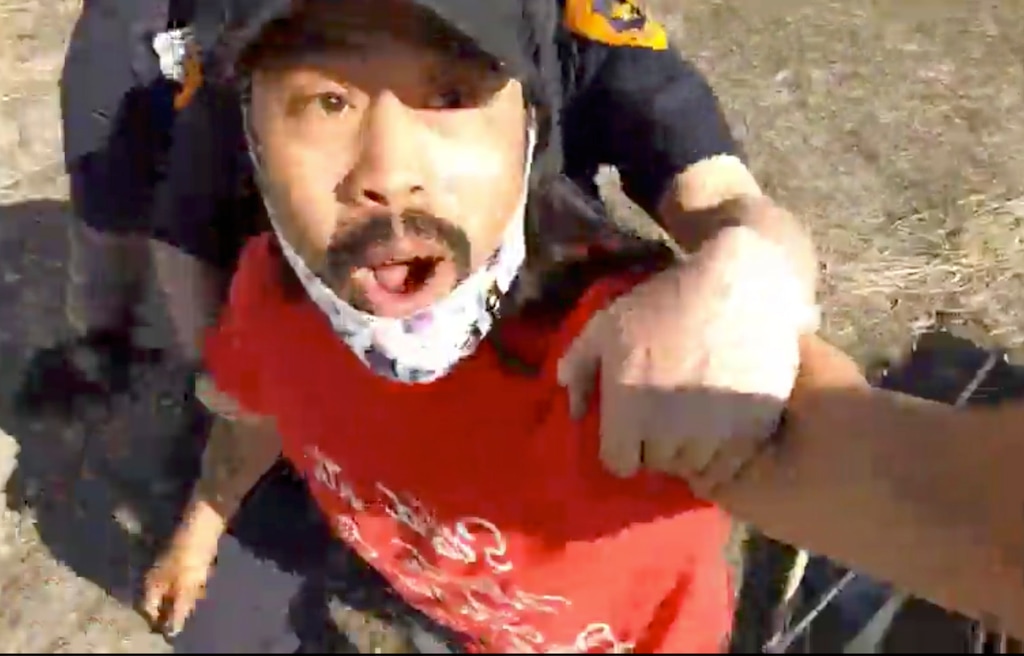 (Screengrab from video by Carl Moore) Homeless advocate Carl Moore, is arrested for trespassing by the Salt Lake City Police, as he was helping unsheltered people gather their belongings, in a field near Cornell Street, on Thursday, March 4, 2021.