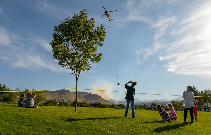 Leah Hogsten  |  The Salt Lake Tribune   Homeowners who were not allowed to return to their homes and onlookers waited near Herriman Cove pond to watch as a firefighting helicopter refilled. A 50-acre wildfire in Rose Canyon was threatened about a half-dozen homes Wednesday, Sept. 12, 2018. A spokesman for Unified Fire said the blaze has already burned a few structures, including outhouses and sheds. Firefighters have evacuated around 20 to 30 homes in two neighborhoods near 15555 S. Rose Canyon Road in Herriman. 