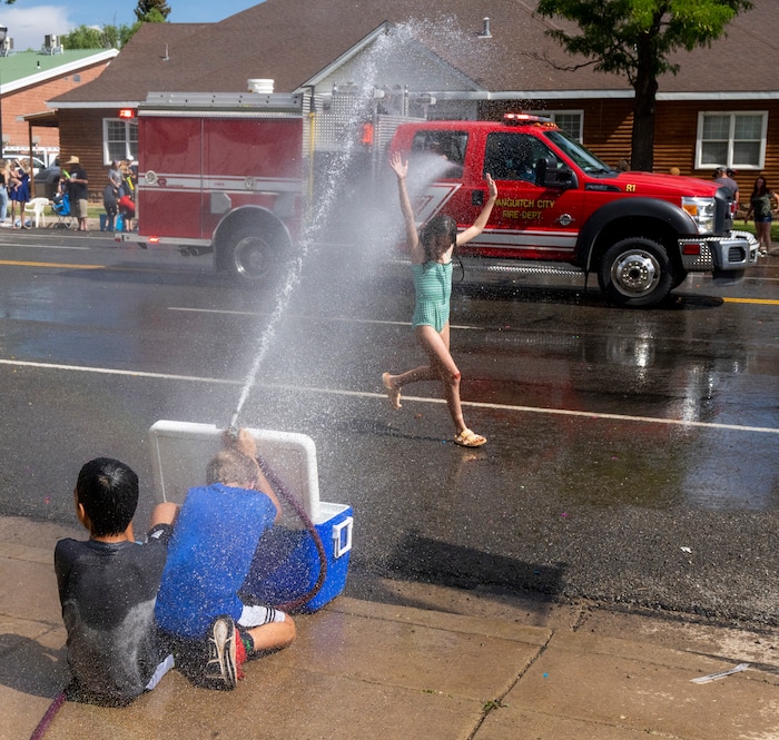 (Rick Egan | The Salt Lake Tribune) 
A girl gets caught in the crossfire, during a water fight between John Leaetoa, 10, and Brigs Mitchell, 9 as they spray a garden hose at the fire truck during the Pioneer Day Parade on Center Street in Panguitch, on Saturday, July 23, 2022.