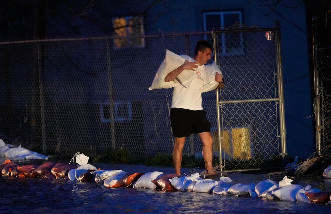 (Francisco Kjolseth | The Salt Lake Tribune) People work to protect homes into the night along 1700 South in Salt Lake City from the rising flow of Emigration Creek through Wasatch Hollow Park on Wednesday, April 12, 2023. 