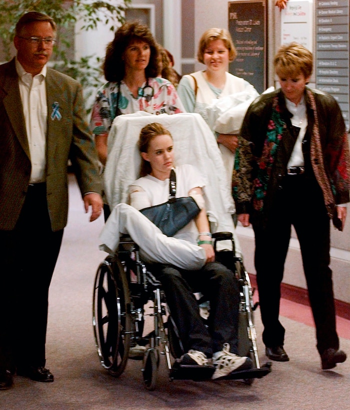FILE - In this May 1, 1999, file photo, Kacey Ruegsegger, 17, is wheeled from a Denver hospital by Patty Anderson, center, after being released. Walking beside her are her parents Greg, left, and Darcy, right. Ruegsegger Johnson survived a shotgun blast during the 1999 shootings at Colorado's Columbine High School that left 12 students, one teacher, and both gunmen dead. (AP Photo/Ed Andrieski, File)