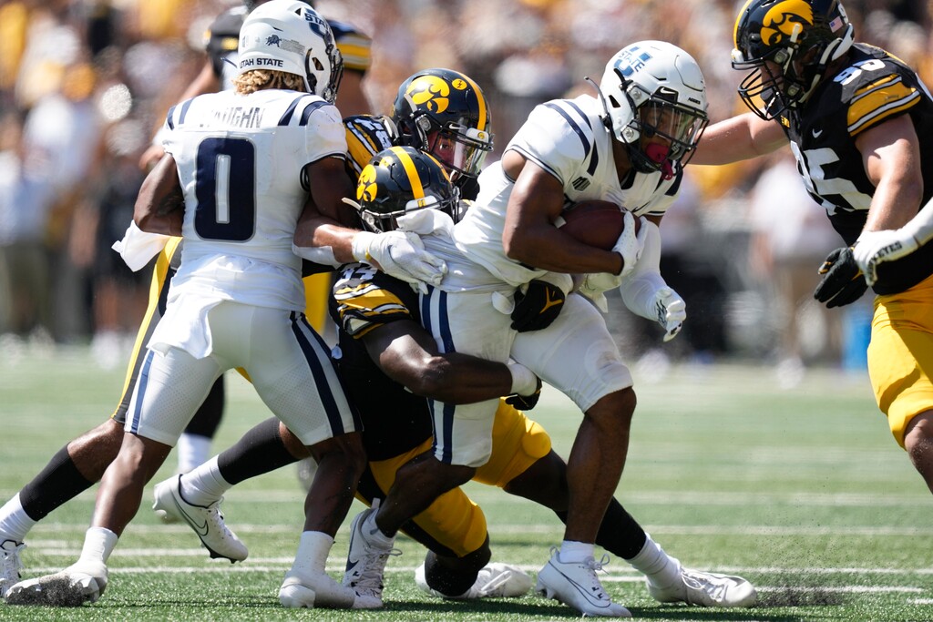 (Charlie Neibergall | AP) Utah State wide receiver Micah Davis (4) is tackled by Iowa linebacker Jay Higgins (34) during the first half Saturday in Iowa City.