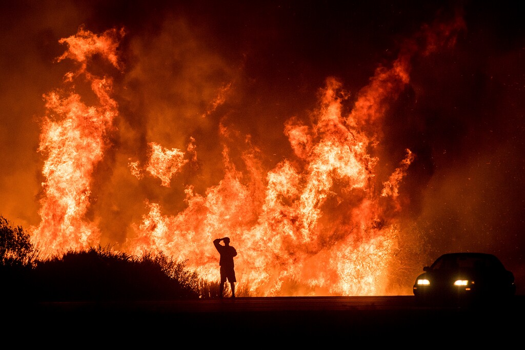 FILE - In this Dec. 6, 2017, file photo, a motorists on Highway 101 watches flames from the Thomas fire leap above the roadway north of Ventura, Calif. There's a sense of relief at the U.S. Forest Service because of the billions of additional dollars made available by lawmakers over the next decade to fight catastrophic wildfires but also a duty to spend it wisely. (AP Photo/Noah Berger, File)