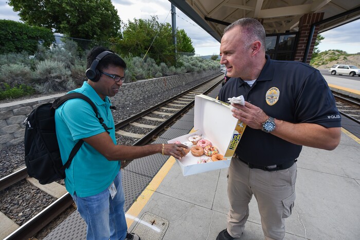 (Francisco Kjolseth | The Salt Lake Tribune) Venu Vandanapu accepts a free donut from interim Sandy Police Chief Bill O'Neal as he entices morning commuters into a free donut In honor of National Donut Day while joined by on Friday, June 1, 2018, at the Sandy Civic Center TRAX Station. The Sandy Police department and Sandy Mayor Kurt Bradburn teamed up in an effort to create positive interactions with residents.