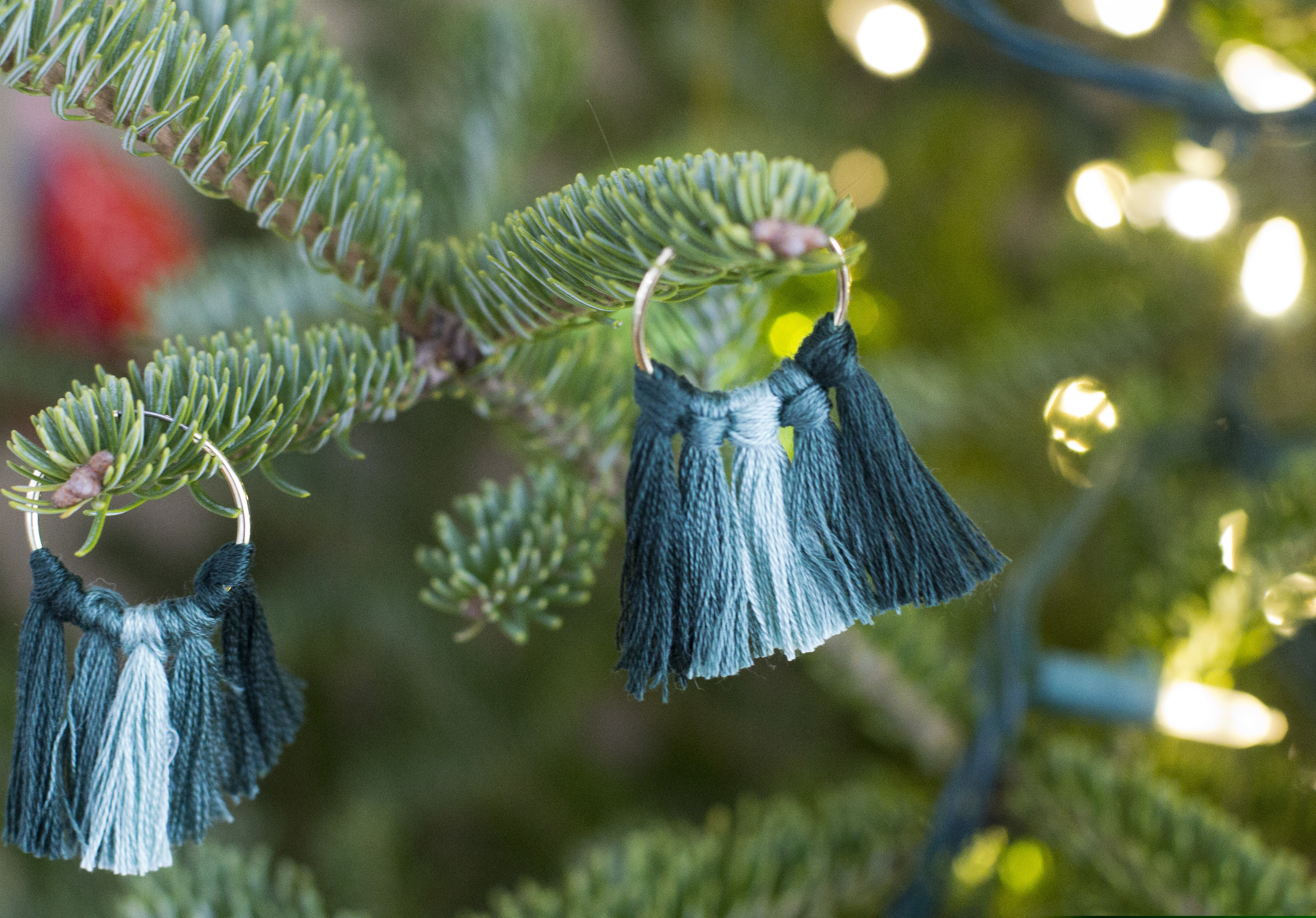 (Holly Ramer | The Associated Press) This Dec. 17, 2018 photo shows handmade earrings hanging on a Christmas tree in Hopkinton, N.H. These shown here combine two trends: tassels and an ombre color pattern.