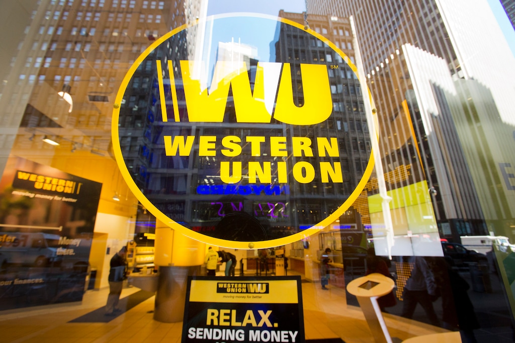 (Mark Lennihan | The Associated Press)Midtown buildings are reflected in the window of a Western Union store, Wednesday, April 5, 2016 in New York. The financial services company is known for person-to-person money transfers and money orders.