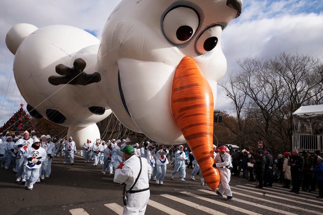 (Mark Lennihan | AP)  A balloon handler holds the Olaf balloon by the nose as strong winds keep Macy's Thanksgiving Day Parade balloons low to the ground, Thursday, Nov. 28, 2019, in New York.