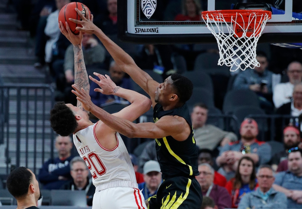 (AP Photo/John Locher) Oregon's Francis Okoro, right, tries to block a shot by Utah's Timmy Allen during the second half of an NCAA college basketball game in the quarterfinals of the Pac-12 men's tournament Thursday, March 14, 2019, in Las Vegas.