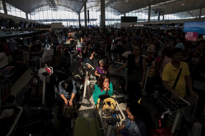 (Vincent Thian | AP Photo) A beam of sunlight is cast on the travelers as they wait at the check-in counters in the departure hall of the Hong Kong International Airport in Hong Kong, Tuesday, Aug. 13, 2019. Protesters clogged the departure area at Hong Kong's reopened airport Tuesday, a day after they forced one of the world's busiest transport hubs to shut down entirely amid their calls for an independent inquiry into alleged police abuse.