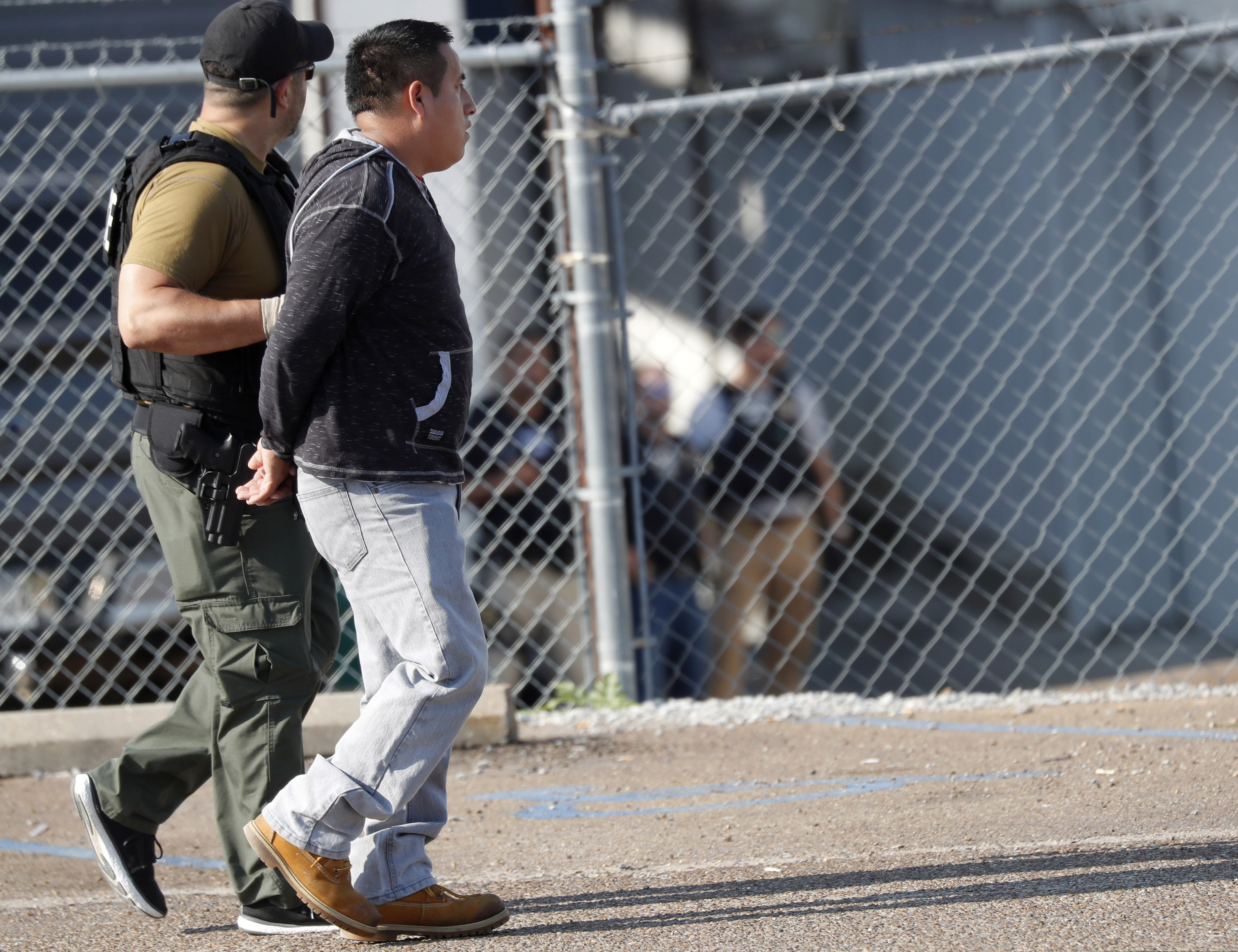 (Rogelio V. Solis | AP) A man is taken into custody as U.S. immigration officials raided the Koch Foods Inc., plant in Morton, Miss., Wednesday, Aug. 7, 2019. U.S. immigration officials raided several Mississippi food processing plants and signaled that the early-morning strikes were part of a large-scale operation targeting owners as well as employees.