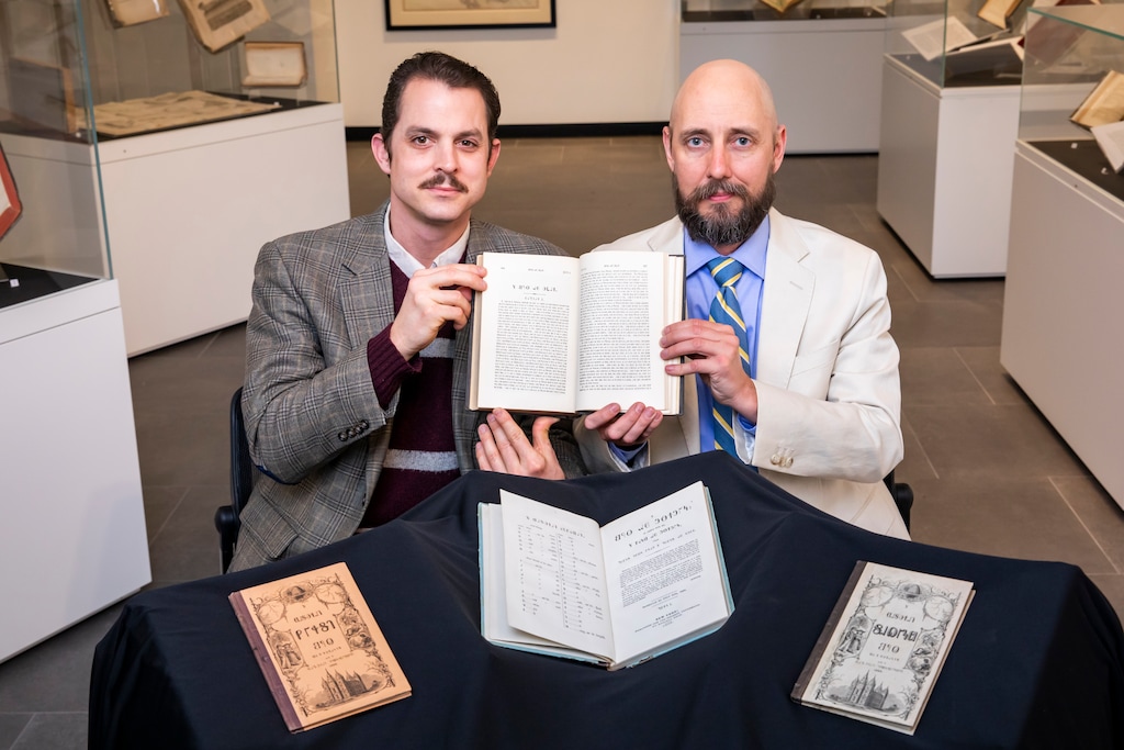 (Michelle Hassel | University of Illinois News Bureau) Computer science professor Neal Davis, left, and linguistics professor Ryan Shosted hold a copy of the Book of Mormon written in the Deseret Alphabet at the Rare Book and Manuscript Library.