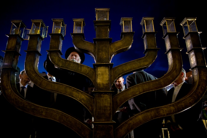 Rabbi Yitzchak Grossman lights candles on the Jewish holiday of Hanukkah at the Western Wall, the holiest site where Jews can pray in Jerusalem's Old City, Thursday, Dec. 14, 2017. (AP Photo/Sebastian Scheiner)