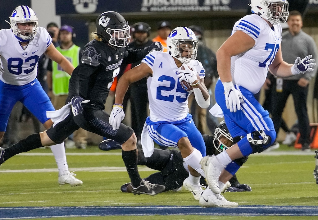 (Leah Hogsten | The Salt Lake Tribune) Brigham Young Cougars defensive back Tyler Allgeier (25) slips past the Aggie defense for a touchdown as the Utah State Aggies host Brigham Young University Cougars at Maverik Stadium Oct. 1, 2021. The Cougars attempt a second straight win for the Wagon Wheel, the trophy of the in-state rivalry, while the Aggies will try to recapture the trophy.