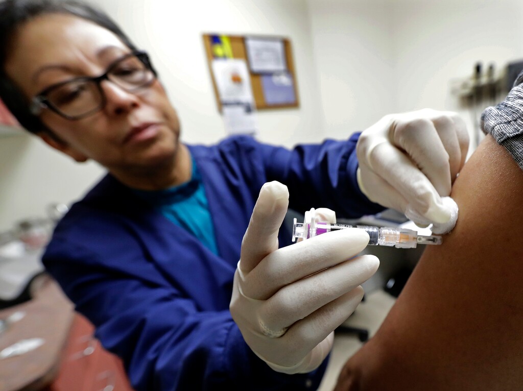 Ana Martinez, a medical assistant at the Sea Mar Community Health Center, gives a patient a flu shot, Thursday, Jan. 11, 2018 in Seattle. According to an update by the Centers for Disease Control and Prevention released Friday, Jan. 12, 2018, flu is now widespread in every state except Hawaii, but the good news is the flu season appears to be peaking. (AP Photo/Ted S. Warren)
