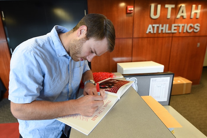 (Francisco Kjolseth  |  The Salt Lake Tribune)  Michael Ruckert, signs a photo book for University of Utah athletic director Chris Hill as he gets ready to say goodbye to friends and staff at the Huntsman Center on Friday, June 1, 2018, after 31 years on the job.