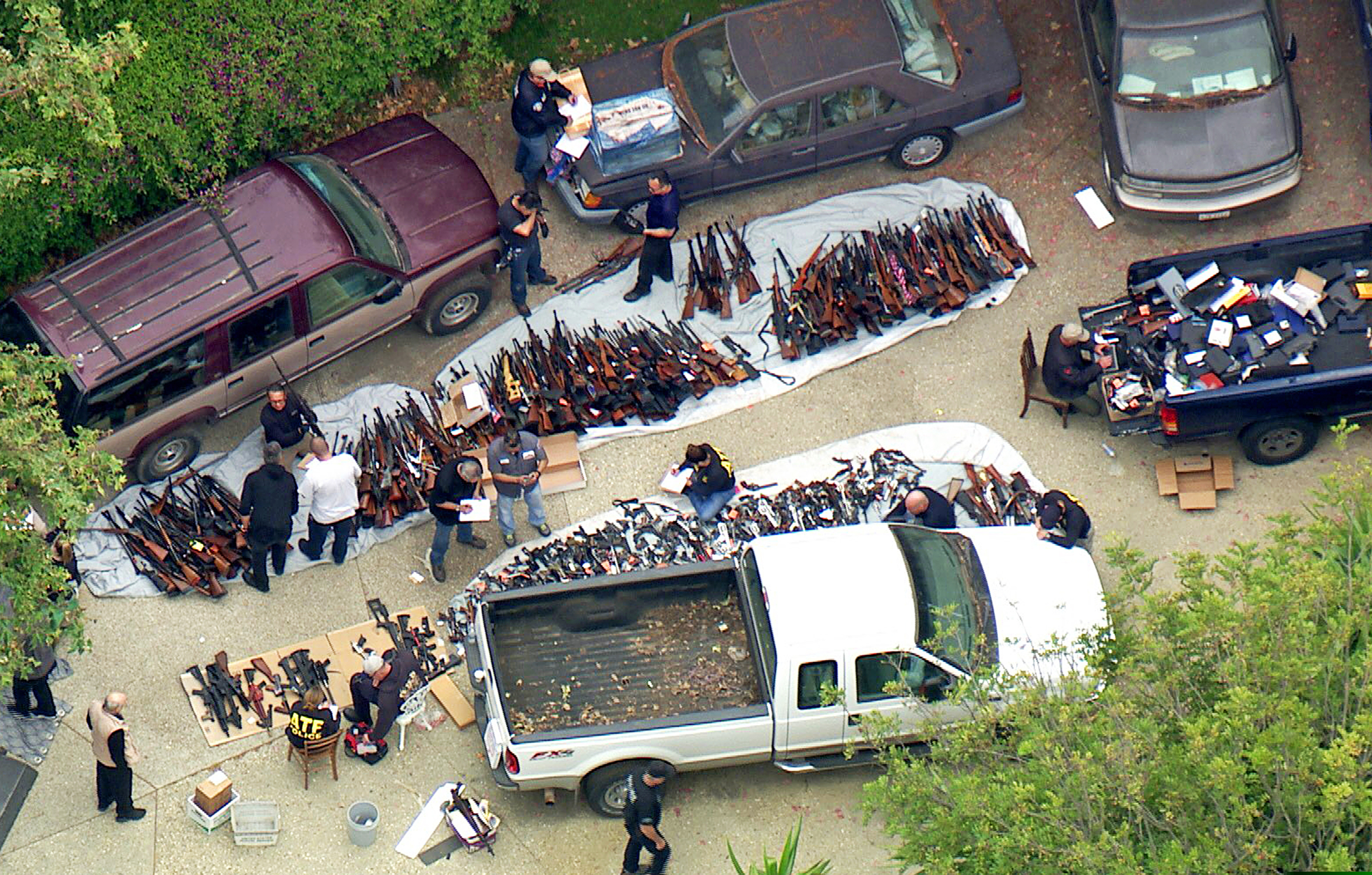 (KCBS/KCAL-TV via AP) This photo from video provided by KCBS/KCAL-TV shows investigators from the U.S. Bureau of Alcohol, Tobacco, Firearms and Explosives and the police inspecting a large cache of weapons seized at a home in the affluent Holmby Hills area of Los Angeles Wednesday, May 8, 2019. Authorities seized more than a thousand guns from the home after getting an anonymous tip regarding illegal firearms sales in a posh area near the Playboy Mansion and served a search warrant around 4 a.m. Wednesday at the property on the border of the Bel Air and Holmby Hills neighborhoods.
