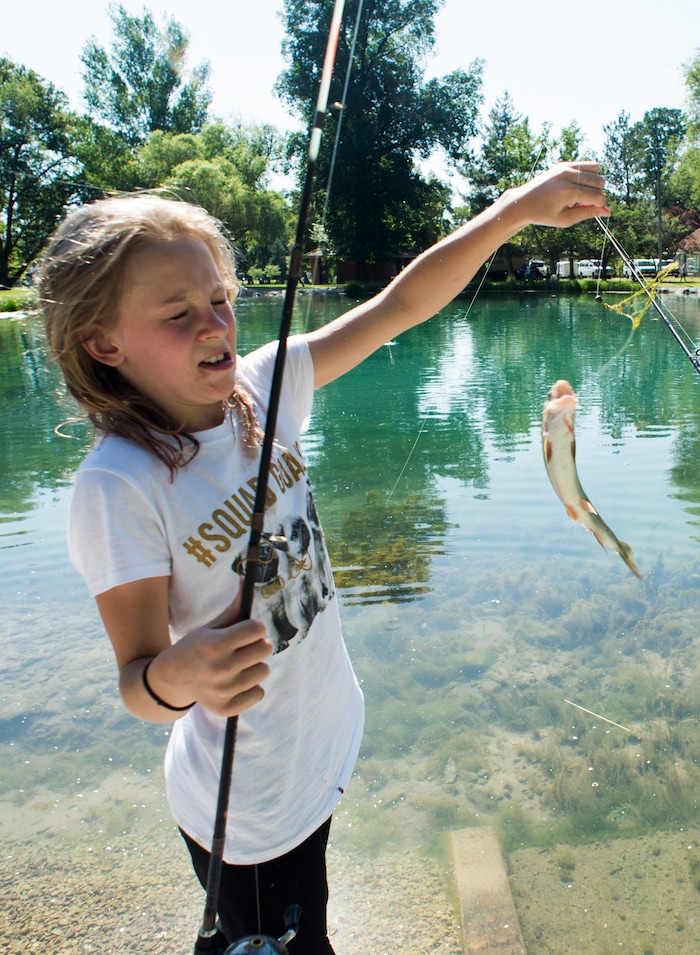 (Rick Egan  |  The Salt Lake Tribune)        Mira Peterson 11, tries to hold on to the fish she caught at Fairmont Park Pond, during the grand reopening celebration, Wednesday, June 27, 2018.
