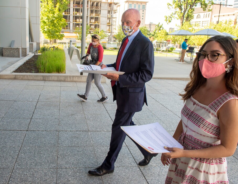 (Rick Egan  |  The Salt Lake Tribune)     Moe Hickey from Voices for Utah Children and Maria Montes walk to the Federal Building in Salt Lake City with petitions signed by thousands of Utahns to present to Utah Sens. Mike Lee and Mitt Romney, urging them to support extending federal COVID-19 relief measures to undocumented workers, Monday, Aug. 10, 2020.