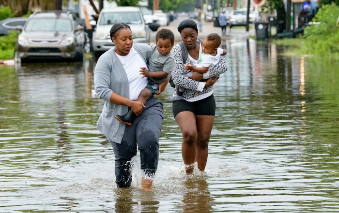 (Matthew Hinton | AP Photo) Jalana Furlough carries her son Drew Furlough as Terrian Jones carries Chance Furlough in New Orleans after flooding Wednesday, July 10, 2019.