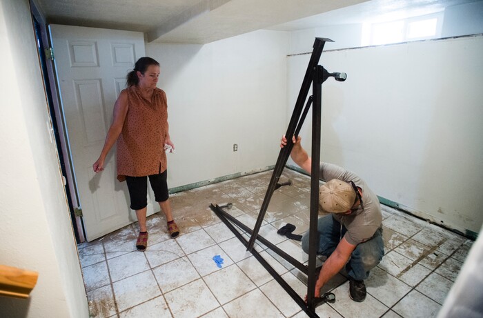 (Rick Egan  |  The Salt Lake Tribune)  Emmy Thomson watches as workers haul everything out of her basement, after sewage water flooded her garage, at her home on Lincoln Street. Tuesday, August 1, 2017.