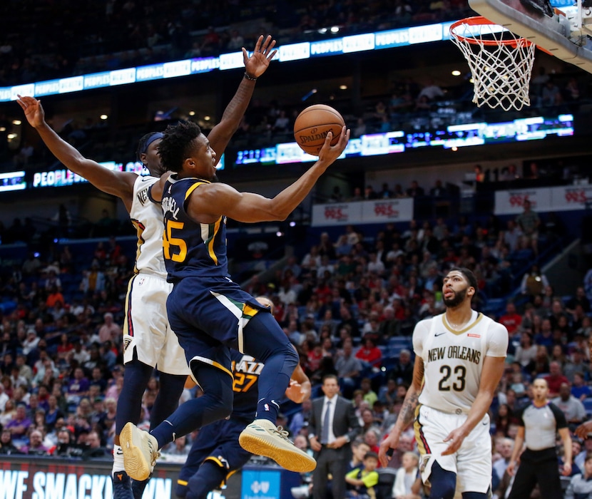 Utah Jazz guard Donovan Mitchell (45) scores against New Orleans Pelicans guard Jrue Holiday (11) in the second half of an NBA basketball game in New Orleans, Sunday, March 11, 2018. (AP Photo/Scott Threlkeld)