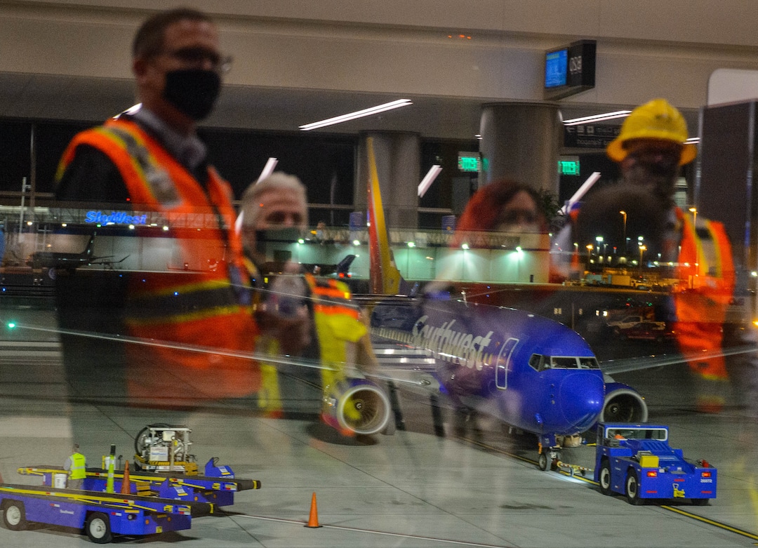 (Trent Nelson  |  The Salt Lake Tribune) Workers reflected in the window look on as the first flight from concourse B at the Salt Lake City International Airport, a Southwest flight to Oakland, prepares to take off on Tuesday, Oct. 27, 2020.