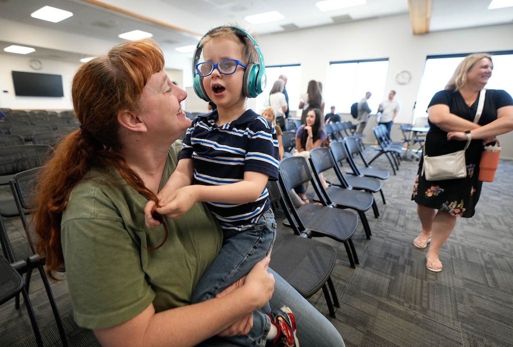 (Francisco Kjolseth | The Salt Lake Tribune) Molly Barrington is joined by her son Jonny, 9, who she said has special needs, at an Alpine School District board of education meeting on Friday, June 30, 2023. Utah’s largest school district will implement a new “consolidated” special education class structure this fall, which will force roughly 150 special education students in grades K-6 to transfer to different schools.