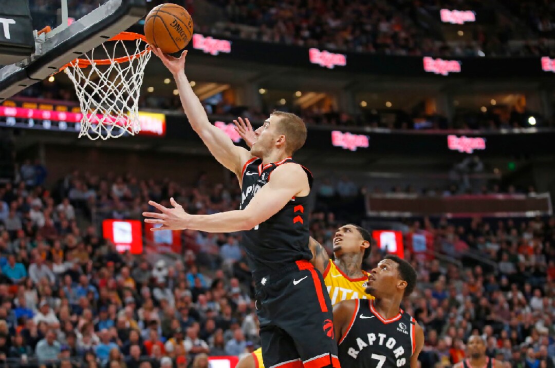 Toronto Raptors guard Matt Thomas, left, lays up the ball as Utah Jazz guard Jordan Clarkson, rear, defends and Raptors guard Kyle Lowry (7) looks on in the first half during an NBA basketball game Monday, March 9, 2020, in Salt Lake City. (AP Photo/Rick Bowmer)