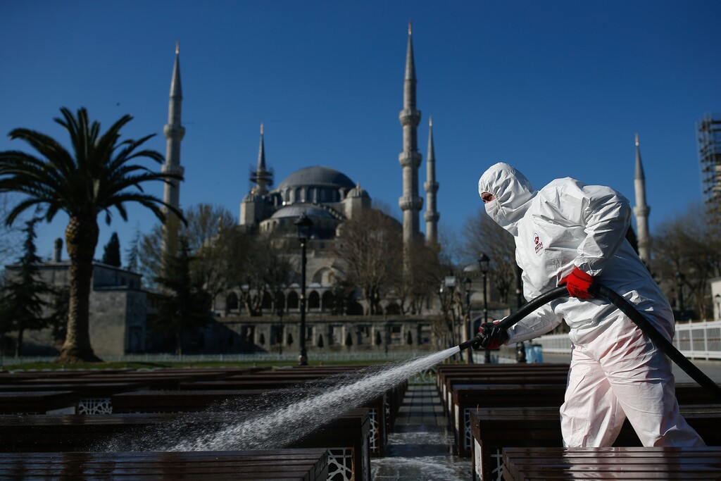 A municipality worker wearing a face mask and protective suits disinfects chairs outside the the historical Sultan Ahmed Mosque, also known as Blue Mosque, amid the coronavirus outbreak, in Istanbul, Saturday, March 21, 2020. The new COVID-19 coronavirus can cause mild or moderate symptoms, but for some it can cause severe illness. (AP Photo/Emrah Gurel)