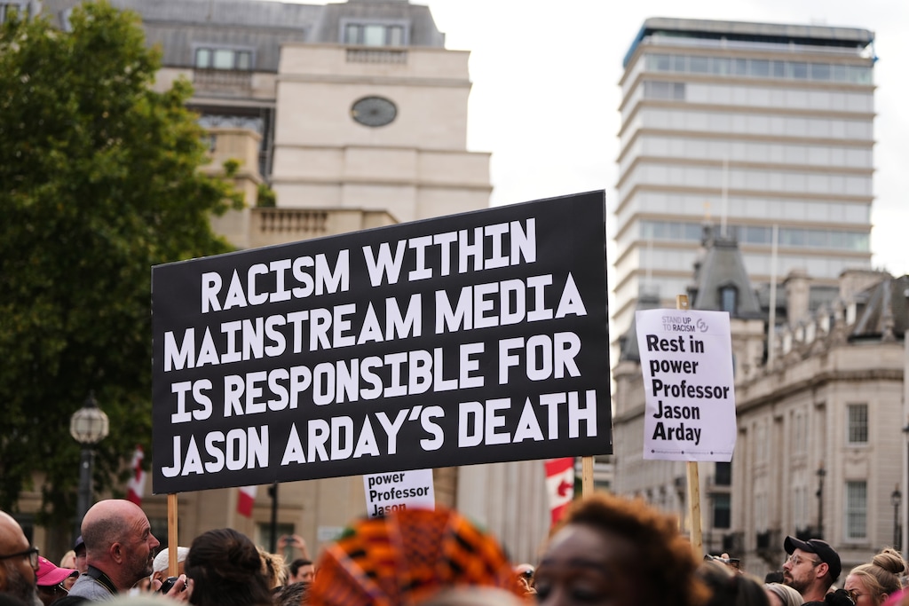 People hold signs during a vigil held by Stand Up to Racism in memory of late University of Cambridge professor Jason Arday at Trafalgar Square in London, Monday, Aug. 17, 2026. (AP Photo/Kirsty Wigglesworth)