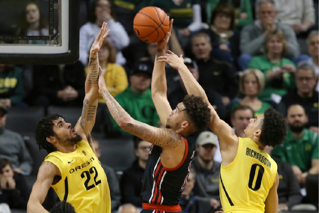 Oregon's Addison Patterson, left, and Will Richardson, right, pressure Utah's Timmy Allen during the first half of an NCAA college basketball game in Eugene, Ore., Sunday, Feb. 16, 2020. (AP Photo/Chris Pietsch)