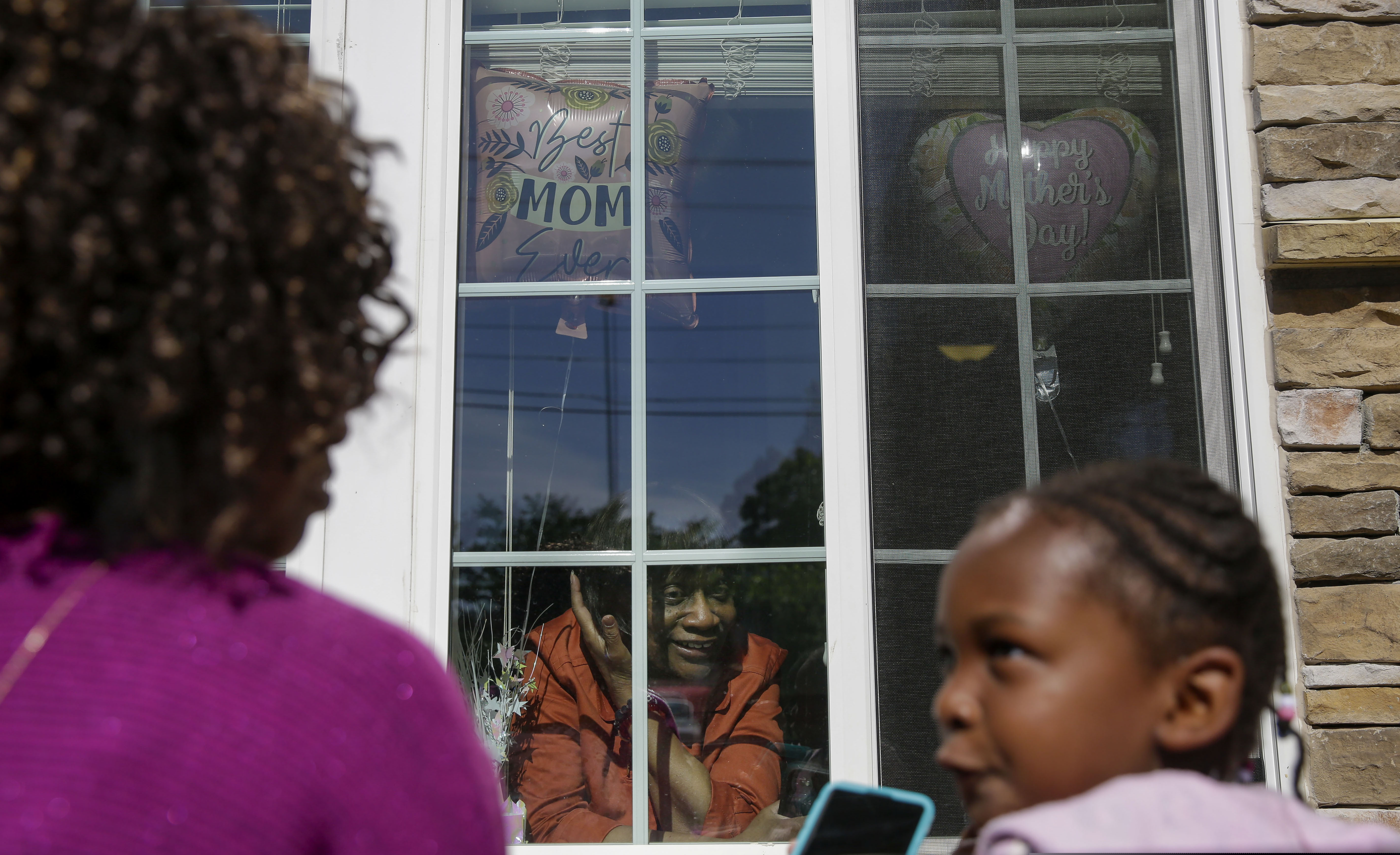 (Brynn Anderson | The Associated Press) Mary Washington, 73, speaks through a window to her daughter, Courtney Crosby and grandchild Sydney Crosby for a Mother's Day celebration at Provident Village at Creekside senior living on Sunday, May 10, 2020, in Smyrna, Ga.